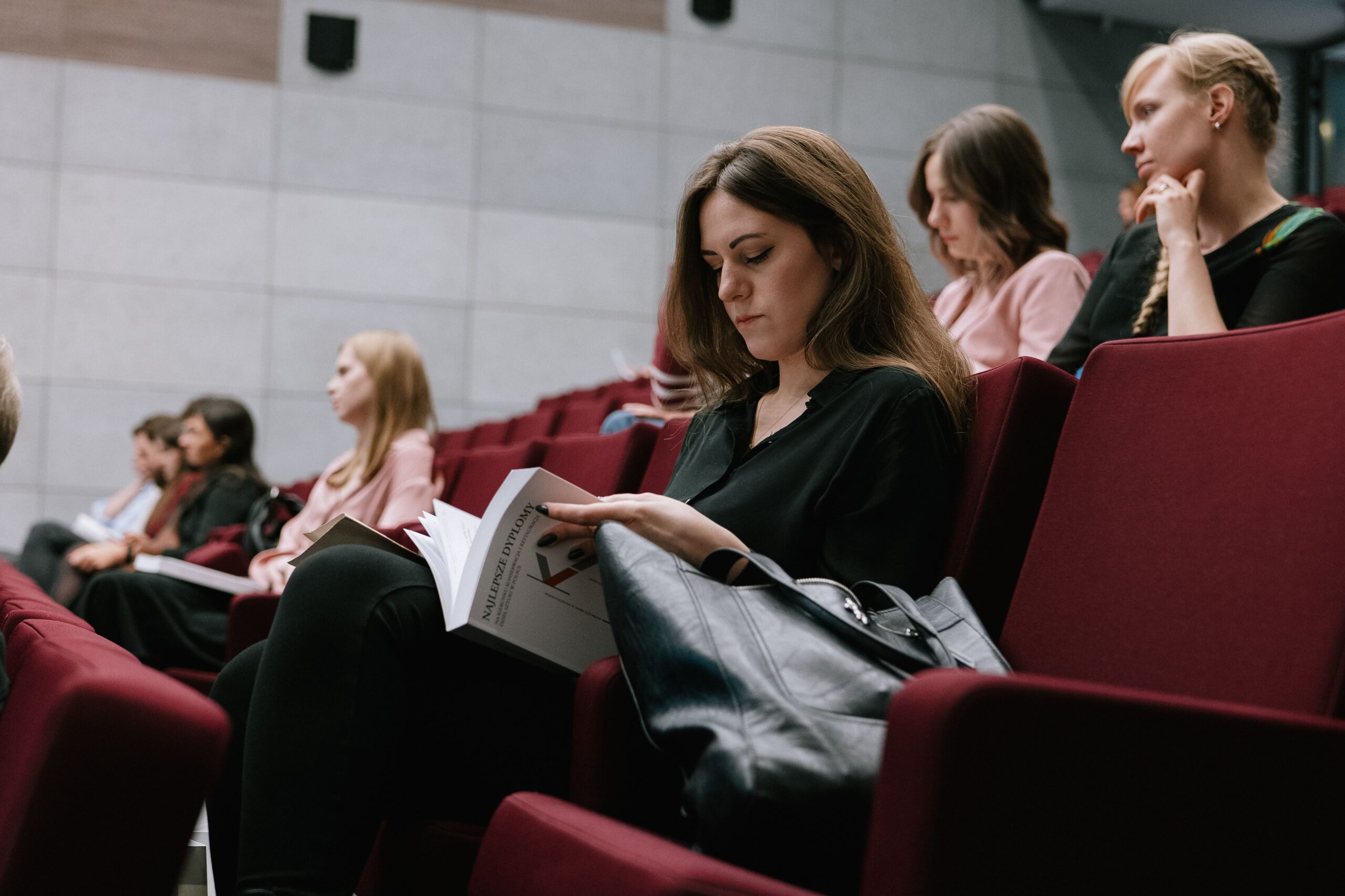 Zbliżenie na siedzącą kobietę przeglądającą książkę Najlepsze dyplomy na kierunku konserwacja i restauracja dzieł sztuki w Polsce