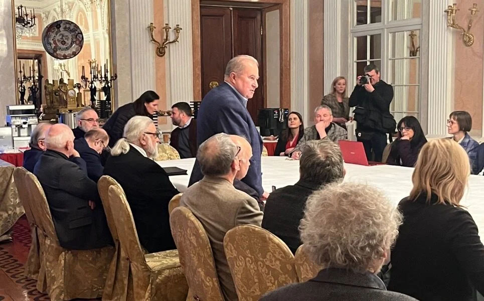 Prezes SKZ Jacek Rulewicz w trakcie przemówienia. Wszyscy siedzą wokół dużego stołu, prezes stoi